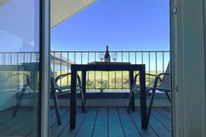 Ein Balkon mit Tisch und Stühlen, einer Weinflasche und einem Glas.