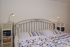 A bed with a metal headboard, two bedside tables with lamps, and storage shelves. - Holiday home in Duhnen with Wi-Fi and parking (Duhnen)