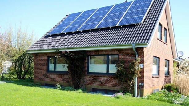 Een huis met een schuin dak en zonnepanelen.