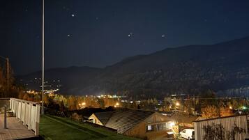 Bairro residencial com casas, um mastro com bandeira e céu noturno claro.