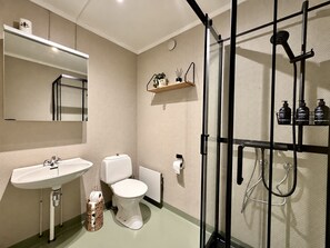 Ett badrum med handfat, toalett och en duschavdelning med glasväggar.