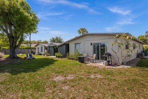 A modern house with a patio, a barbecue grill, and a tree. - Lake Patio + Firepit + Grill | Mins to Vanderbilt Beach | Fisherman's Cottage (Naples)