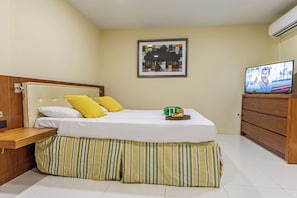 Une chambre d’hôtel avec un lit, une télévision, un tableau encadré au mur et une commode en bois.