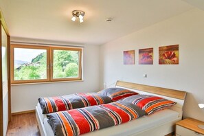 Ein Schlafzimmer mit einem Bett, einem Fenster und drei an der Wand befestigten Kunstwerken.