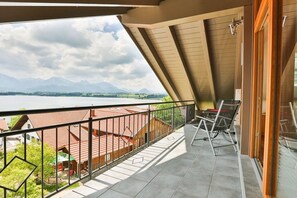 Ein Balkon mit Blick auf einen See und Berge, ein Stuhl und ein Tisch.