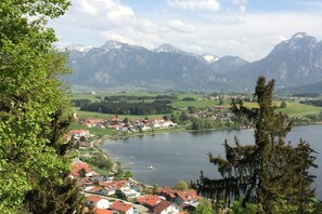 Eine Stadt am Seeufer mit Häusern, einem Steg und Bergen im Hintergrund.