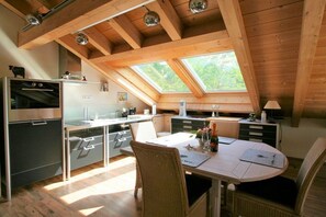 Cozinha moderna com claraboias, área de jantar com mesa e cadeiras, e forno embutido.