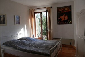 Un dormitorio con cama, una ventana con cortinas, un cartel en la pared y un radiador.