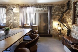 A room with a stone wall, a wooden table, leather chairs, a small potted plant, and a lamp. - Villa in Kornic, Krk with swimming pool (Kornic, Krk)