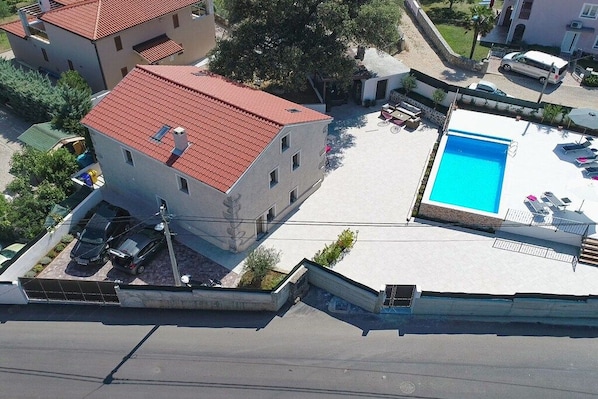 Un immeuble résidentiel avec un toit recouvert de tuiles rouges, une piscine et un espace de stationnement.