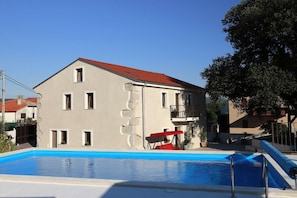 Un bâtiment doté d’une piscine, d’une chaise rouge et d’un balcon.