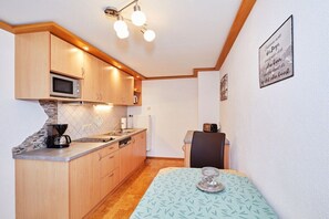 Eine kompakte Küche mit Holzschränken, einer Mikrowelle, einer Kaffeemaschine und einem Toaster.