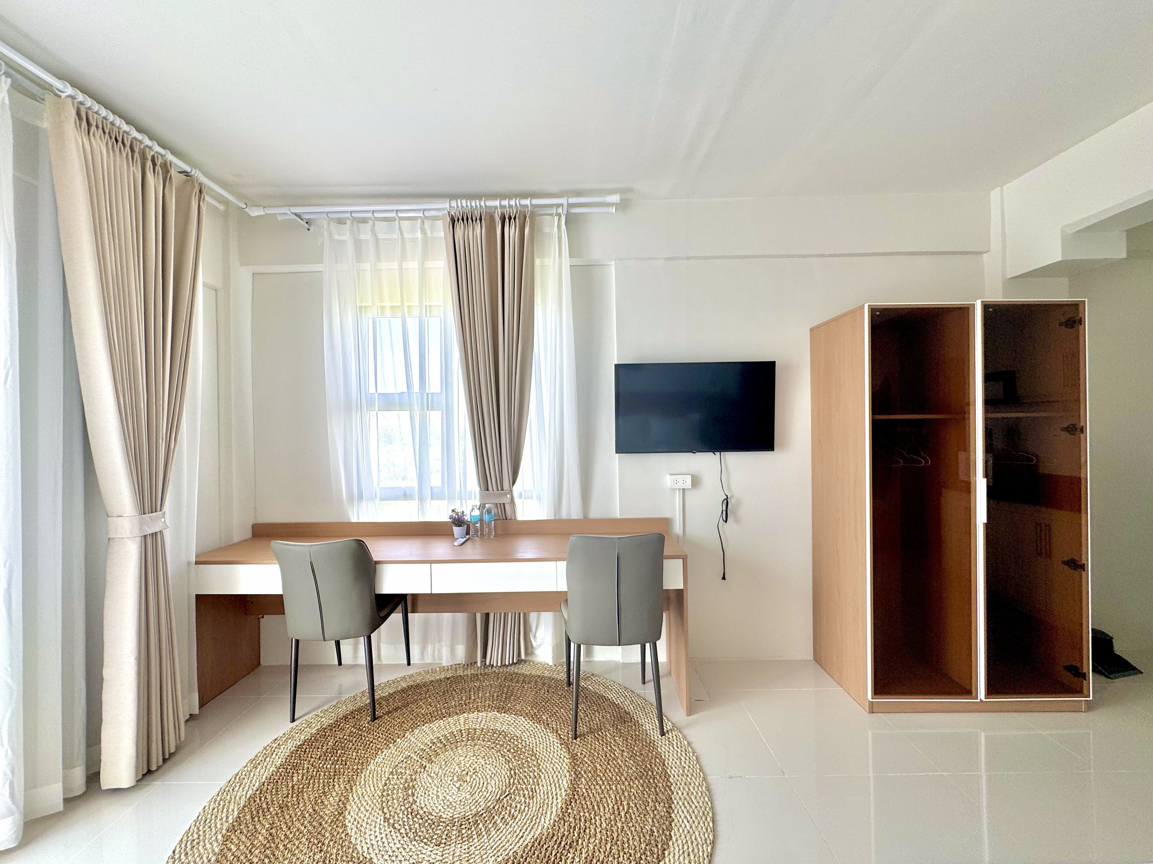 A modern room with a desk, two chairs, a television, and a wardrobe.