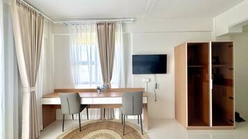 A modern room with a desk, two chairs, a television, and a wardrobe.