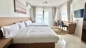Ein Hotelzimmer mit einem Bett, einem Schreibtisch, einem Sessel, einem Fernseher und einem Fenster mit Vorhängen.