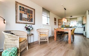 A dining area with wicker chairs, a wooden table, and a wall-mounted light fixture. - Nice home in Stevensweert with WiFi (Stevensweert)