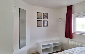 Un dormitorio con una cama, un armario blanco, un espejo y cuatro cuadros en la pared.