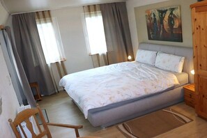 A bedroom with a bed, curtains, a painting, and a wooden cabinet. - Becker Holiday Winery Apartment "Hasenläufer" (Burgen)
