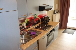 A compact kitchen with a sink, stove, and microwave. - Becker Holiday Winery Apartment "Hasenläufer" (Burgen)