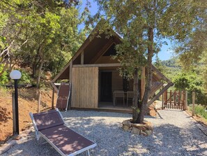 A wooden cabin with a covered entrance, a bench, and a gravel path.