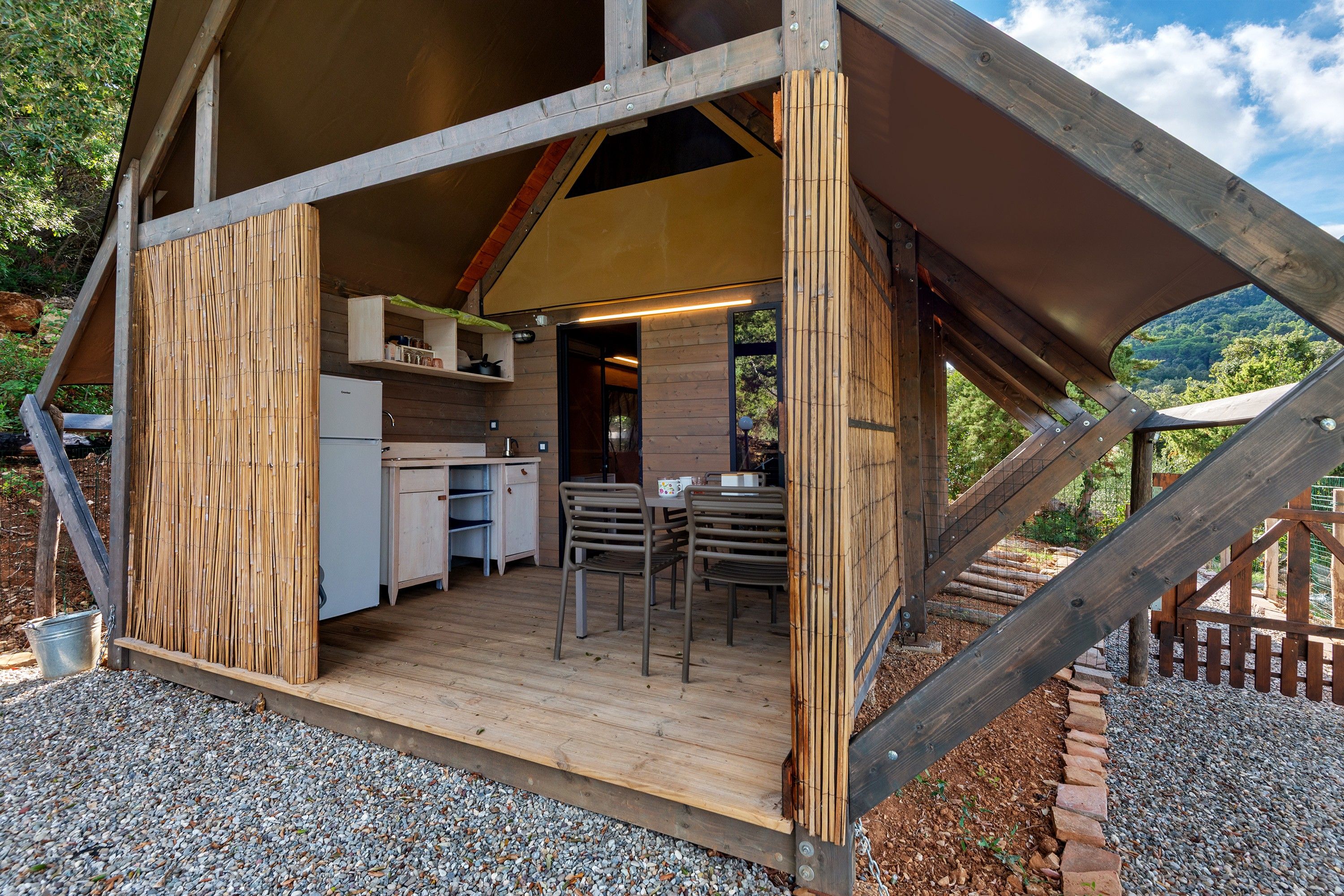 A wooden cabin with a kitchen, dining area, and a view of the surrounding forest.