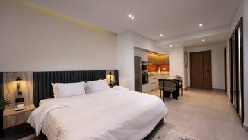 Une chambre d’hôtel moderne dotée d’un grand lit, d’une petite kitchenette et d’un coin repas séparé.