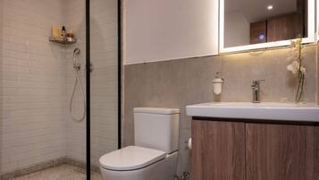 Une salle de bain moderne équipée d’une douche, de toilettes et d’un meuble-lavabo.
