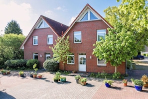 Ein zweistöckiges Backsteinhhaus mit Haustür, Fenstern und einer gepflasterten Auffahrt.