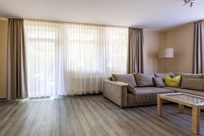 Ein Wohnzimmer mit einer Couch, einem Couchtisch und transparenten Vorhängen.