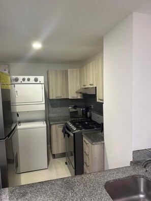 A compact kitchen with a double-door refrigerator, a microwave, and a gas stove. - Feel at Homewith Best View in the City Pool (Santo Domingo)