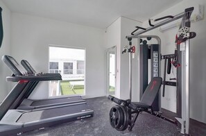 Academia com esteira, banco de musculação e diversos equipamentos de exercício.