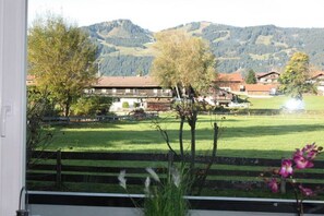 Blick auf eine gebirgige Landschaft mit Gebäuden und einem grünen Feld.