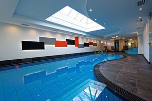 Piscina com claraboia, design curvo e chão em azulejos.