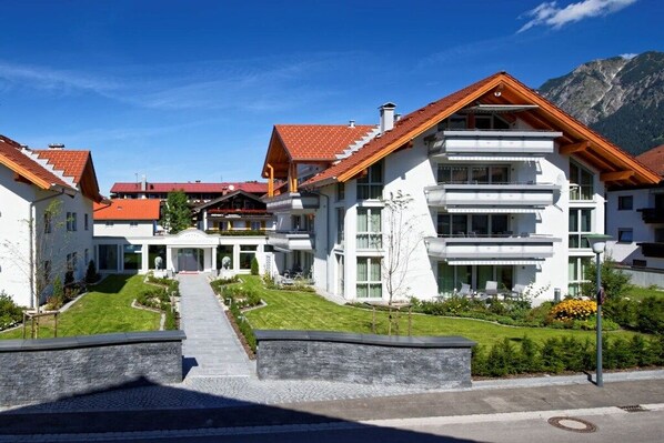 Um edifício moderno de vários andares, com um pátio central, grandes janelas e montanhas ao fundo.