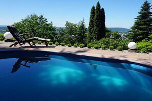 En swimmingpool med liggestole og udsigt over landskabet.