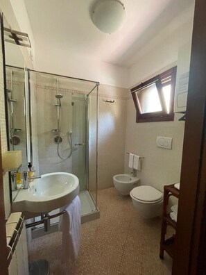 A bathroom with a glass-enclosed shower, a sink, a toilet, and a mirror. - Appartamento 80mq, due camere da letto (porto viro)