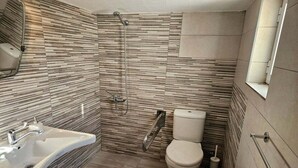 Et stilfuldt badeværelse med bruser, toilet og håndvask.