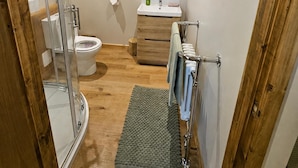 Un baño moderno con cabina de ducha de vidrio, inodoro, lavamanos y espejo.