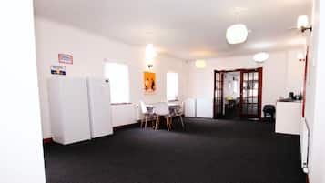 A room with a dining table and chairs, a refrigerator, and a kitchenette area.