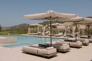 Zona junto a la piscina con tumbonas, sombrillas y una vista despejada del paisaje.