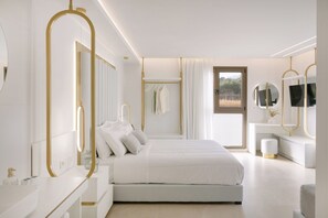 Un dormitorio moderno con una cama grande, mesitas de noche, un tocador con espejo y una ventana con vistas al exterior.
