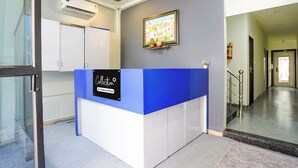 Ein blauer und weißer Empfangstresen, darüber ein gerahmtes Bild und eine Feuerlöscher an der Wand.