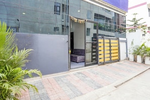 A modern building with a glass facade, a gated entrance, and a paved walkway. - Collection O Satya Sai Square (Indore)