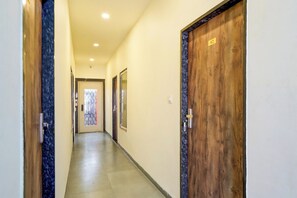 Un pasillo con puertas de madera, piso de baldosas e iluminación empotrada en el techo.