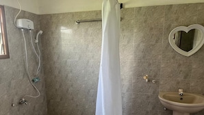 A bathroom with a shower, a sink, and a heart-shaped mirror.
