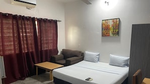 Una habitación de hotel con una cama, un sofá, una mesa y un cuadro en la pared.