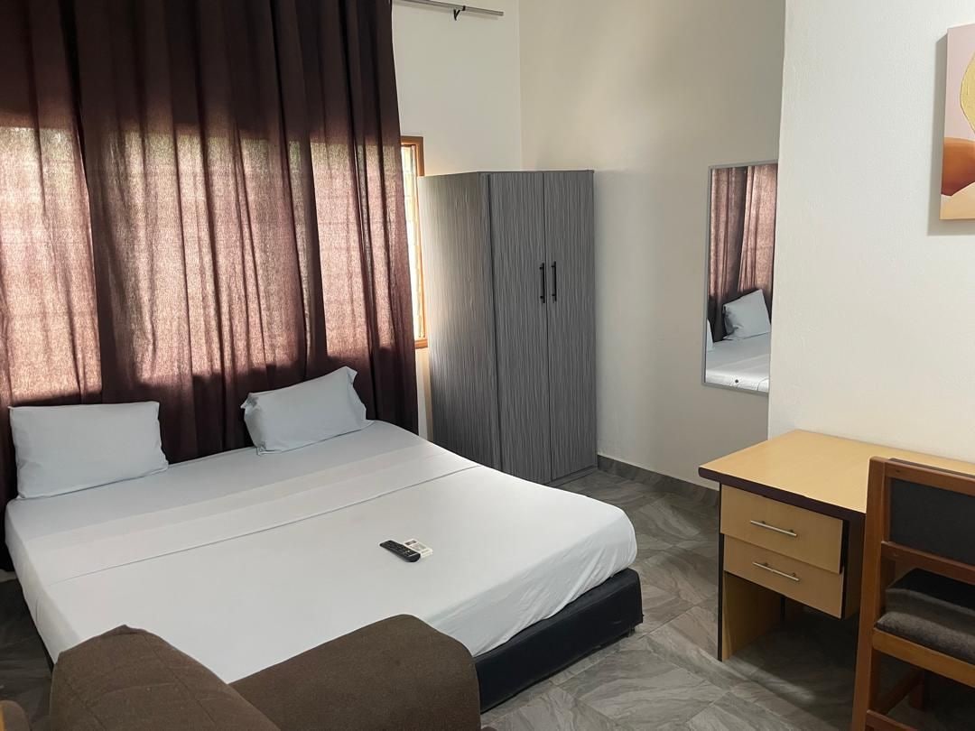 Una habitación de hotel con cama, escritorio, armario y espejo.