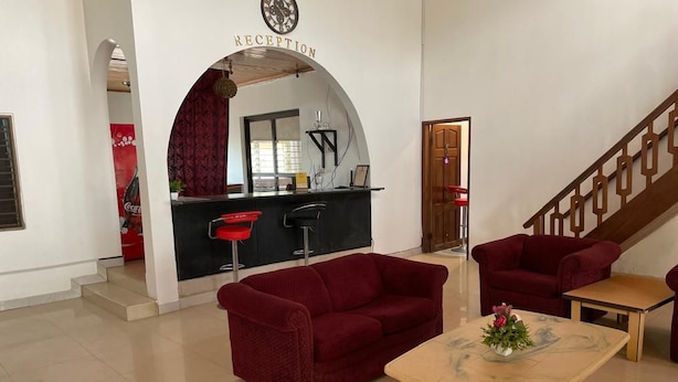 A reception area with a counter, red bar stools, a red sofa, and a coffee table with a flower vase.