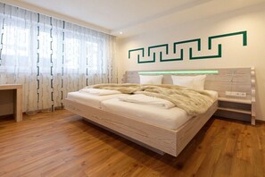 Quarto moderno com cama de madeira, mesa de cabeceira e luminária fixada na parede.