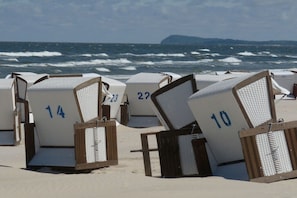 Strandstolar med nummer, placerade på en sandstrand med havet i bakgrunden.